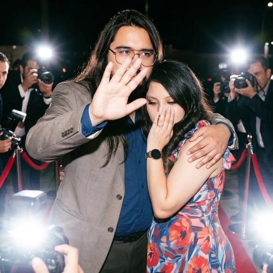 Jesse Lopez and Meli together beneath camera flashes at an evening event